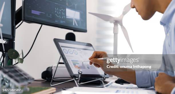 in der nähe der windmühle analysieren ingenieure windkraftanlagen. gemeinsam die nutzung erneuerbarer energien mit wind- und sonnenenergie zu gestalten. konzept der nutzung erneuerbarer energien. - energieeffizienz stock-fotos und bilder