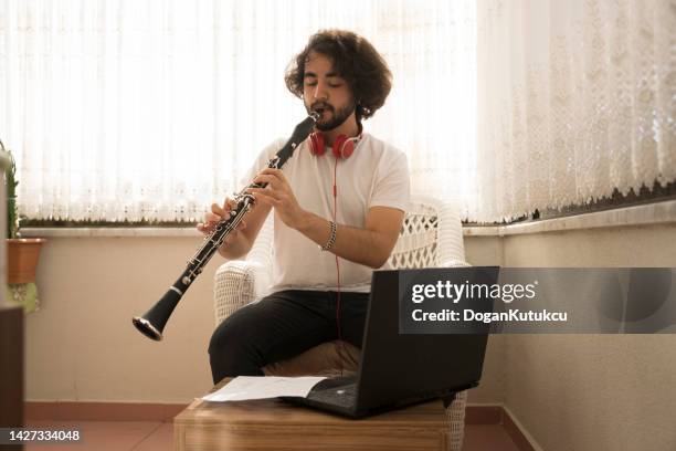 giovane che impara a suonare lo strumento musicale a casa lavoro di formazione online. - flauto foto e immagini stock