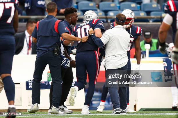 Quarterback Mac Jones of the New England Patriots is helped off the field during the fourth quarter against the Baltimore Ravens at Gillette Stadium...