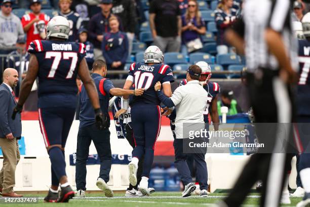 Quarterback Mac Jones of the New England Patriots is helped off the field during the fourth quarter against the Baltimore Ravens at Gillette Stadium...