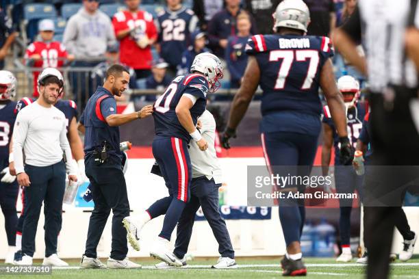 Quarterback Mac Jones of the New England Patriots is helped off the field during the fourth quarter against the Baltimore Ravens at Gillette Stadium...