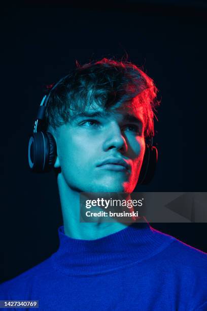 studio portrait of a caucasian young man listening to music with headphones - young caucasian man on black stock pictures, royalty-free photos & images