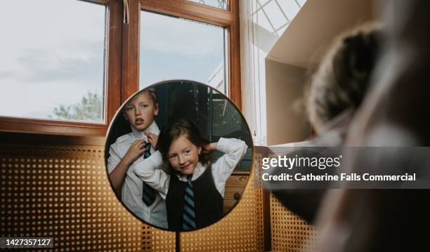 siblings prepare for school, looking in the mirror as they fix their ties - school tie stock pictures, royalty-free photos & images
