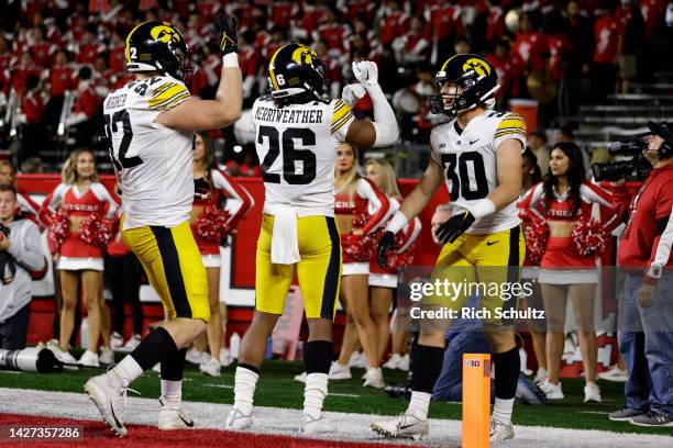 Defensive back Kaevon Merriweather of the Iowa Hawkeyes celebrates his touchdown on a fumble recovery with defensive back Quinn Schulte and defensive...