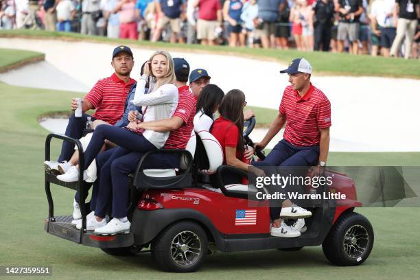 Xander Schauffele of the United States Team is driven off the 18th hole in a cart with wife Maya, Patrick Cantlay and his fiancee Nikki Guidish after...