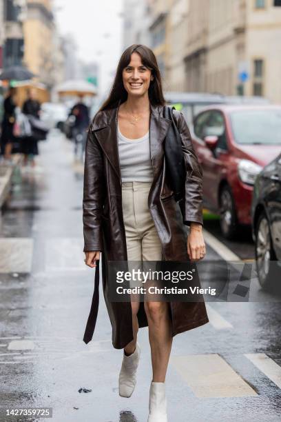 Guest wears brown leather shirt, beige shorts, ankle boots outside Salvatore Ferragamo during the Milan Fashion Week - Womenswear Spring/Summer 2023...