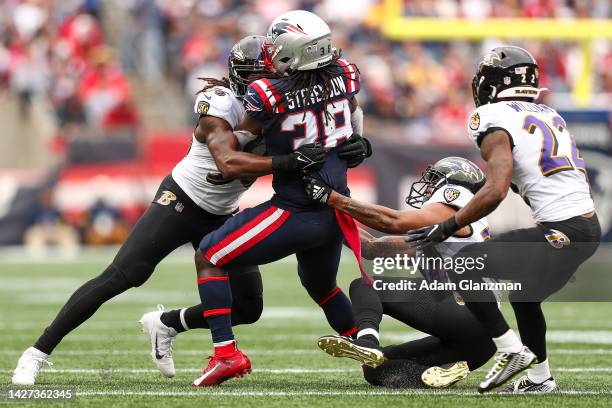 Rhamondre Stevenson of the New England Patriots is tackled by Baltimore Ravens defenders during the third quarter at Gillette Stadium on September...