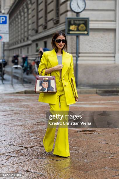 Heart Evangelista wears yellow blazer with slits on the sleeves, flared pants, grey cropped top, sunglasses, Hermes brown beige bag with face print...