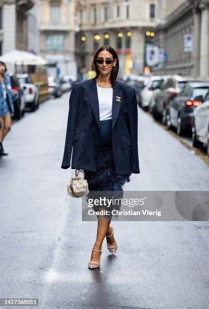Elisa Taviti wears navy oversized double breasted blazer, skirt with fluffy elements, golden bag, Chanel broochj outside Philosophy during the Milan...