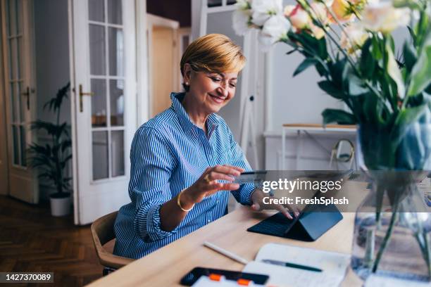 a happy businesswoman transferring money online using her credit - shopping online blue stock pictures, royalty-free photos & images