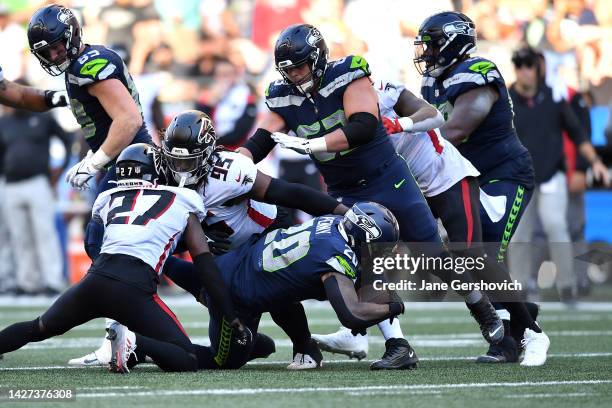 Rashaad Penny of the Seattle Seahawks is tackled by Richie Grant and Ta'Quon Graham of the Atlanta Falcons during the second half at Lumen Field on...
