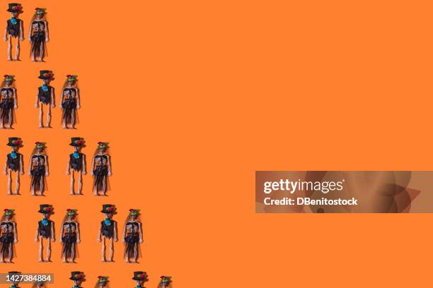 pattern of skeleton couples dressed in gala celebrating halloween, on the left side, on orange background. concept of day of the dead, mexico, all saints' day, skull and crossbones, bones and dolls. - funny skeleton stockfoto's en -beelden