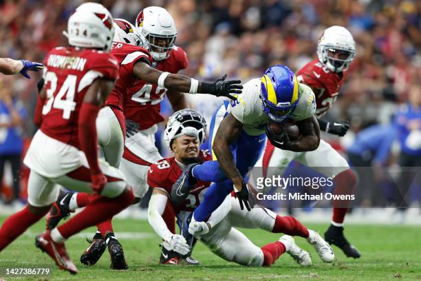 Cam Akers of the Los Angeles Rams dives as Jace Whittaker of the Arizona Cardinals loses his helmet during the second half of a game at State Farm...