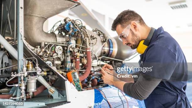 mecánico de aeronaves que fija el motor a reacción y usa multímetro, disparo central - fuselage fotografías e imágenes de stock