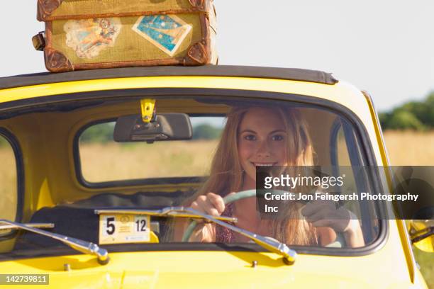 caucasian woman driving car on road trip - yellow suitcase stock pictures, royalty-free photos & images