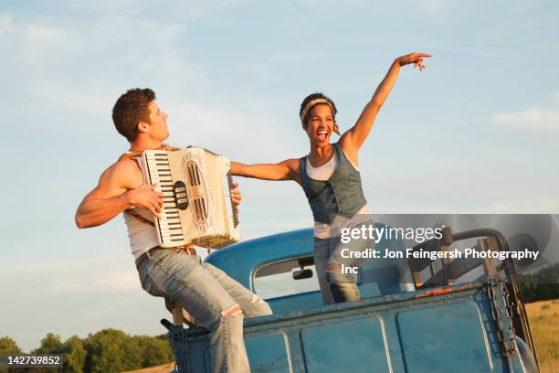 man playing accordion for girlfriend in back of truck - accordion instrument stock-fotos und bilder