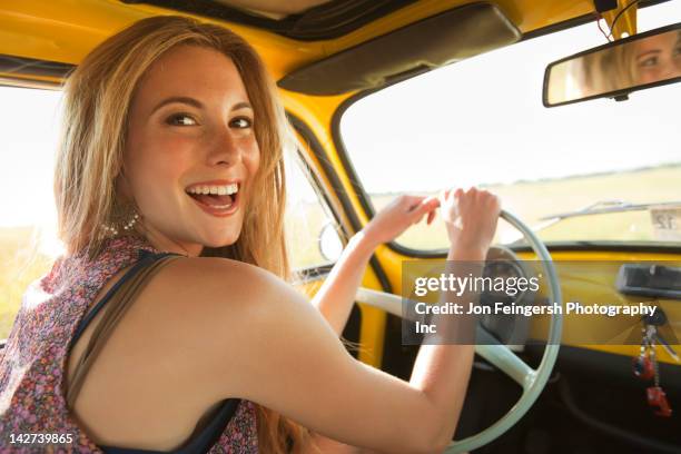 caucasian woman driving old-fashioned car - auslachen blick in die kamera stock-fotos und bilder