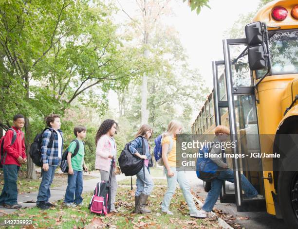 children getting onto school bus - boarding a bus stock-fotos und bilder