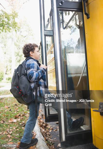 mixed race boy getting onto school bus - boarding a bus stock-fotos und bilder