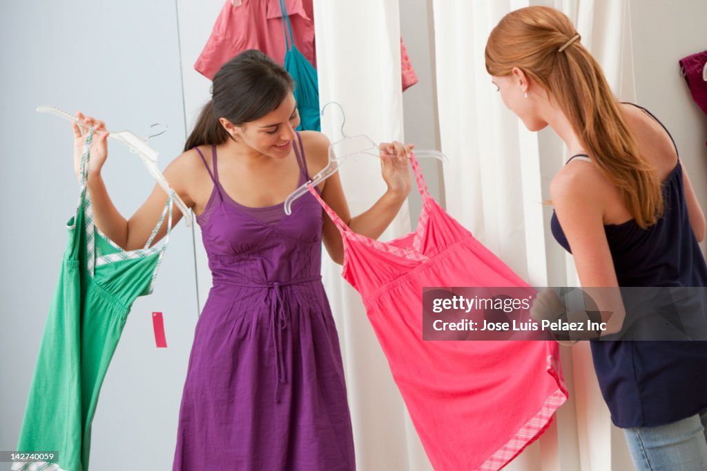 Caucasian girls shopping for dresses in shop