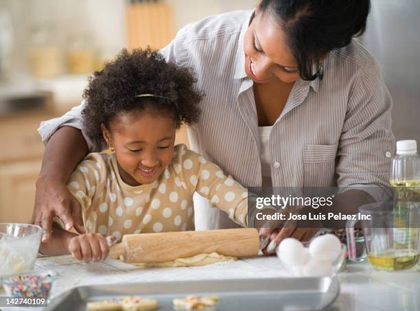 mother and daughter baking in kitchen - black mother and child cooking stock-fotos und bilder