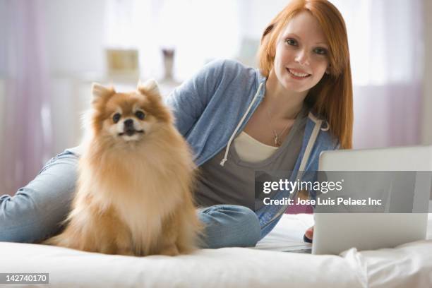 caucasian woman laying on bed with dog - pomeranian - fotografias e filmes do acervo