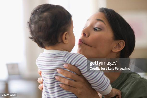 mixed race mother kissing baby boy - poner caras fotografías e imágenes de stock