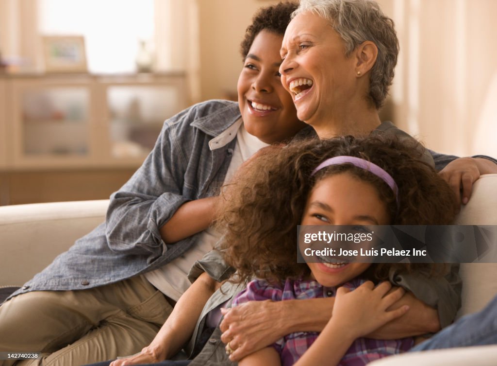 Grandmother and grandchildren laughing on sofa