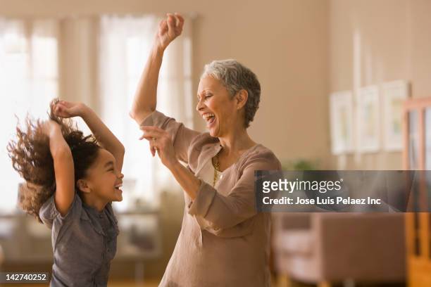 grandmother and granddaughter dancing together - anziani attivi foto e immagini stock