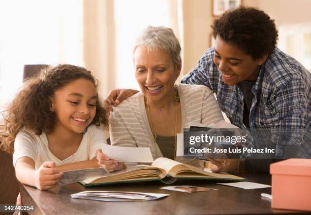 grandmother and grandchildren looking at photographs - história imagens e fotografias de stock