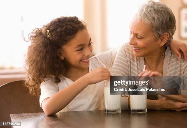 grandmother and granddaughter drinking milk - milk family stockfoto's en -beelden