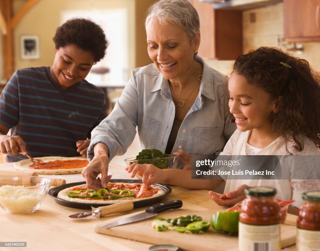 Grandmother and grandchildren making pizza