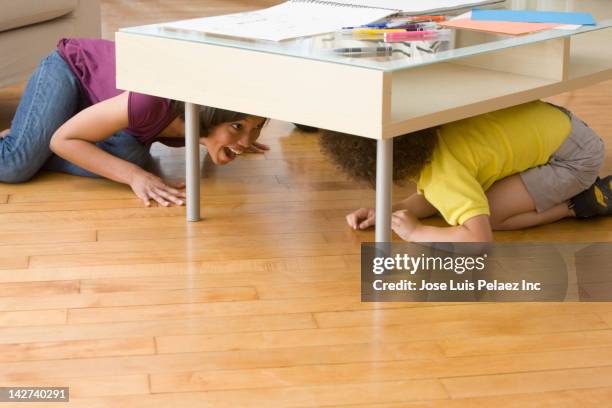 mother and son playing underneath coffee table - kid hide and seek stock pictures, royalty-free photos & images