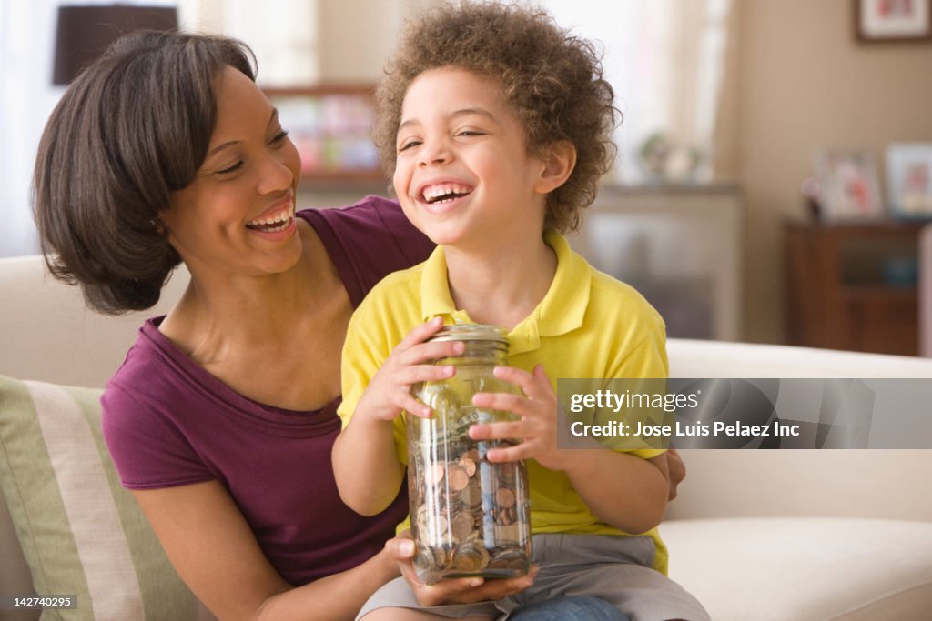 Mother and son holding jar of coins