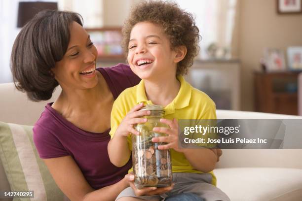 mother and son holding jar of coins - 2 cents stockfoto's en -beelden