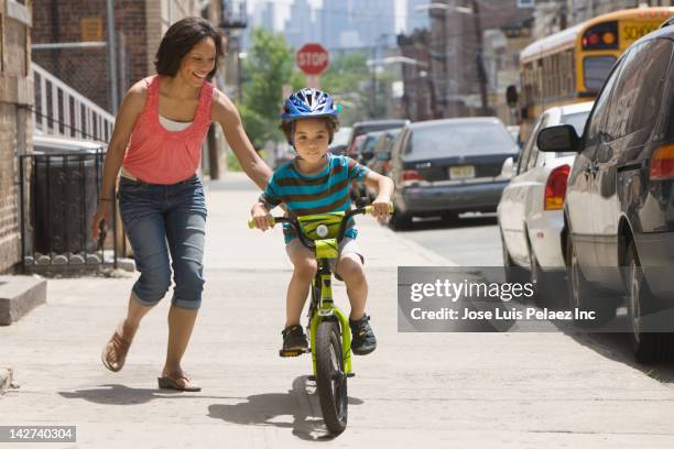 mother teaching son to ride bicycle - west new york new jersey stock-fotos und bilder