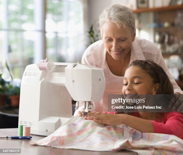 grandmother teaching granddaughter how to sew - stop watch stockfoto's en -beelden