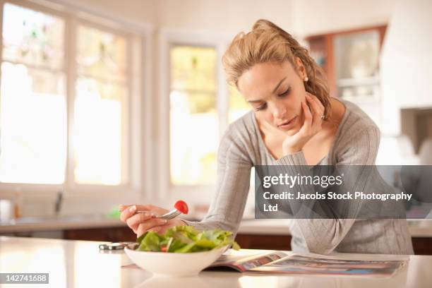 hispanic woman eating salad and reading magazine - diet journal - fotografias e filmes do acervo