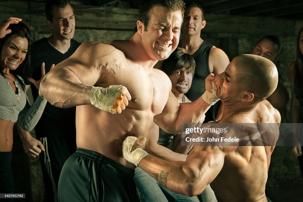 People watching two men boxing without gloves