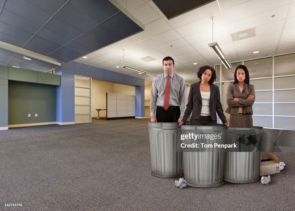 Business people standing with garbage cans in empty office
