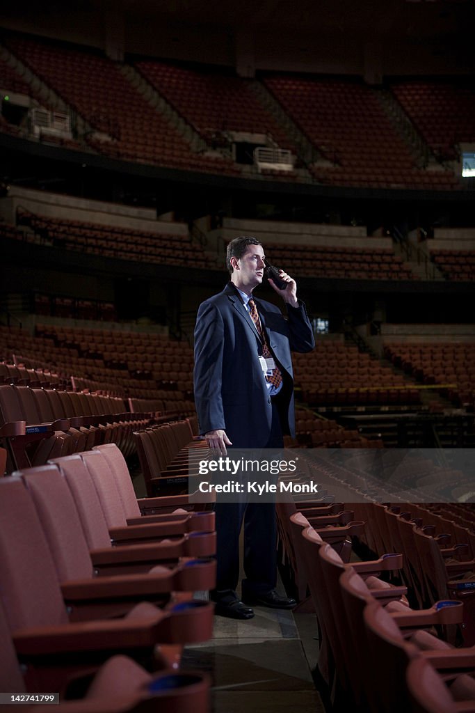 Businessman using walkie-talkie in empty auditorium