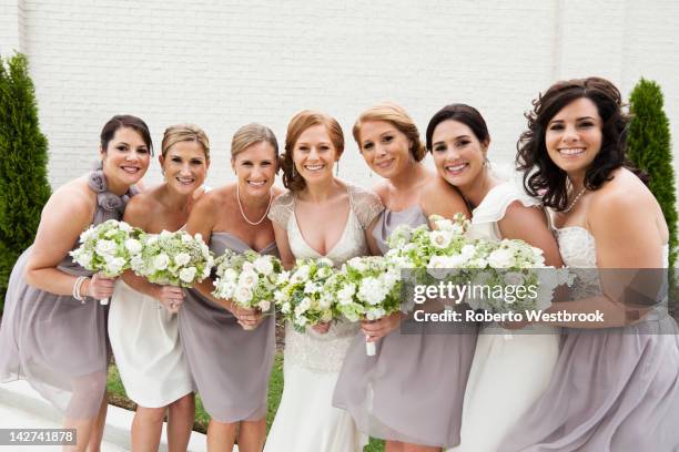 smiling bridal party standing with bride - hochzeitsgesellschaft stock-fotos und bilder