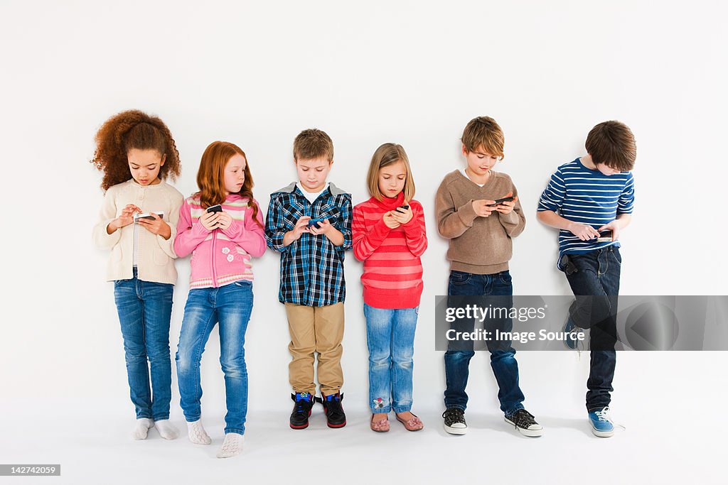 Children using smartphones, standing in a row