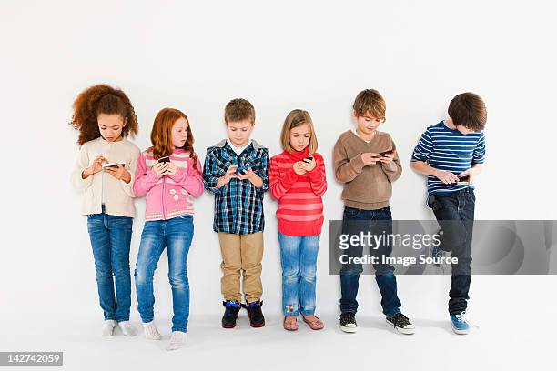 children using smartphones, standing in a row - 10 to 13 years stock pictures, royalty-free photos & images