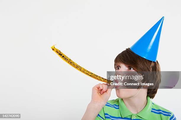 boy blowing party horn blower - party hat stock pictures, royalty-free photos & images