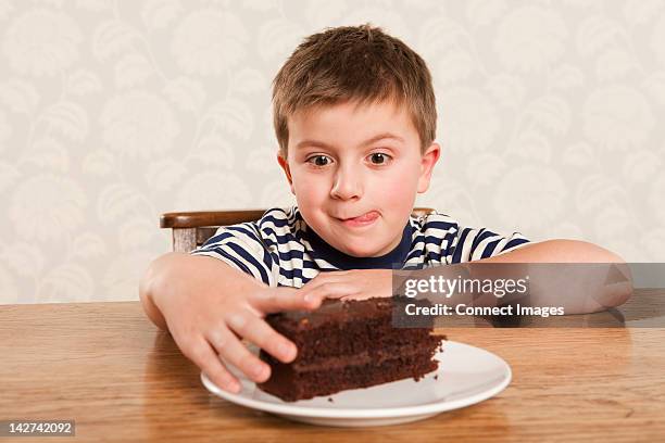 boy reaching for chocolate cake - cake slices stock pictures, royalty-free photos & images