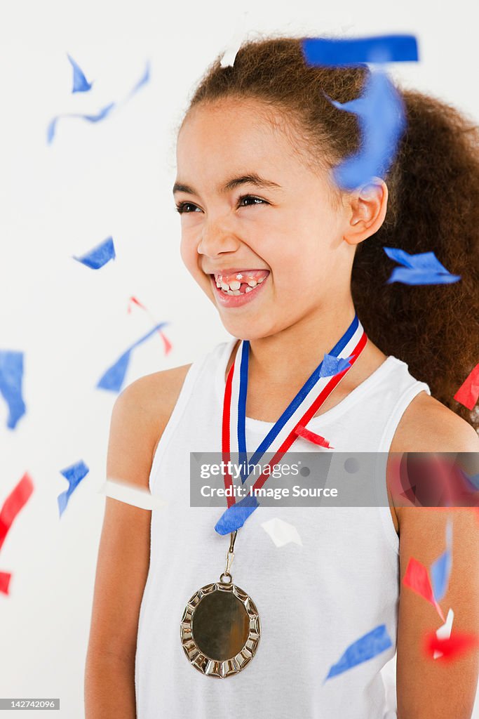 Girl wearing medal with ticker tape falling