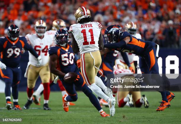 Pat Surtain II of the Denver Broncos punches the ball away from Brandon Aiyuk of the San Francisco 49ers during the first half of a game at Empower...