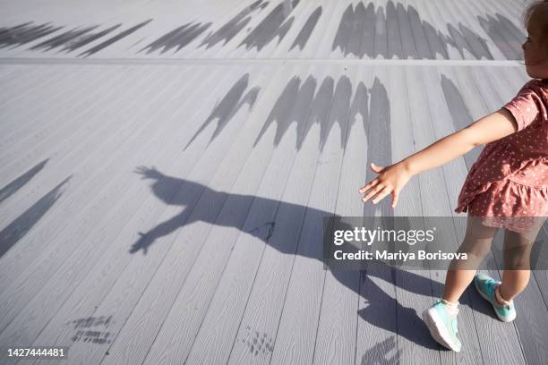 shadows of a girl on a gray wooden veranda. - children playing silhouette stock pictures, royalty-free photos & images