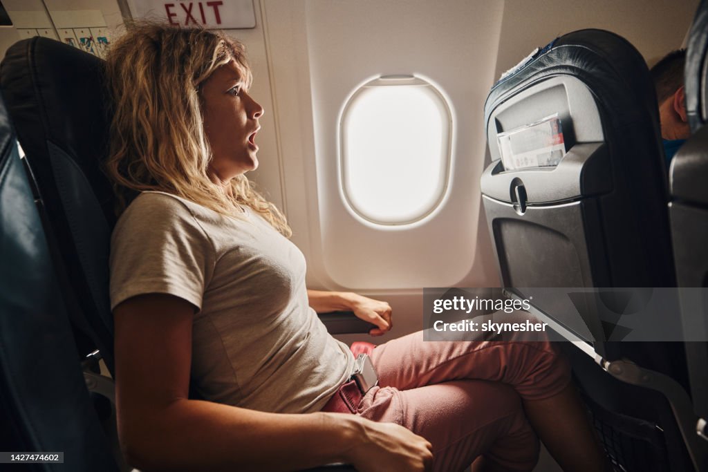 Fearful woman traveling by airplane.